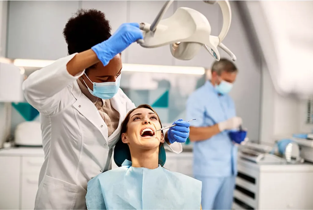 Dentist examining a patient's teeth under an overhead light