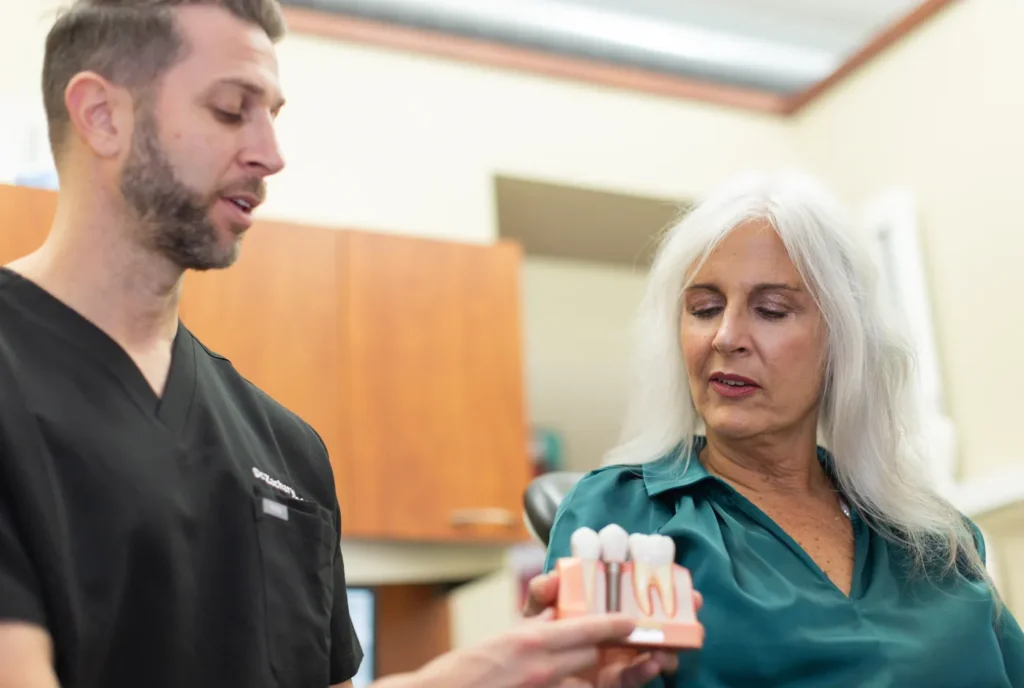 Dr. Zachary Rosen showing a patient a dental implant model