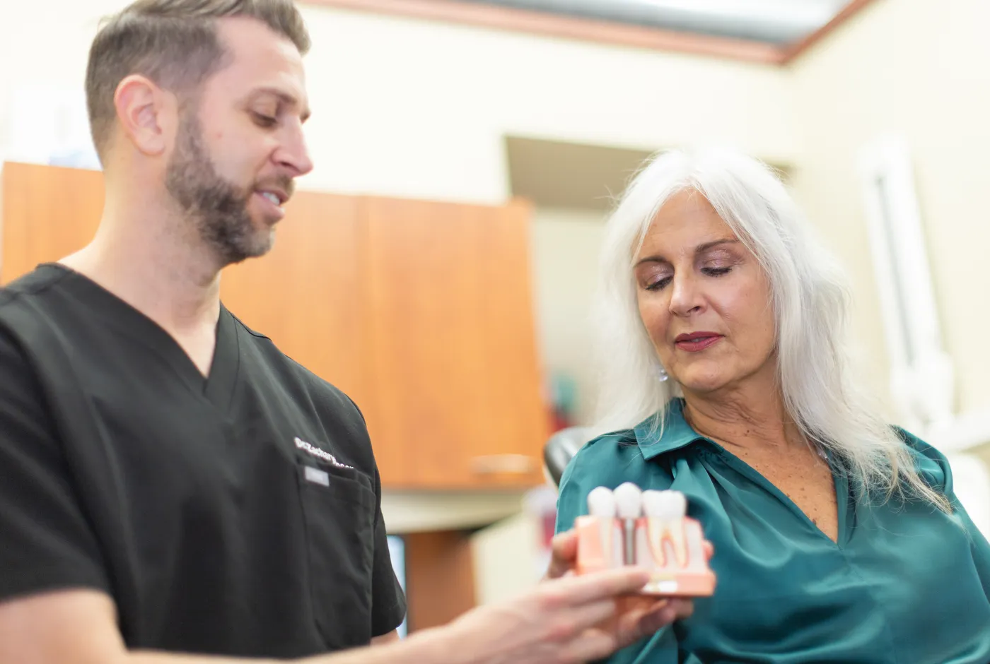 Dr. Zachary Rosen showing a patient a dental implant model